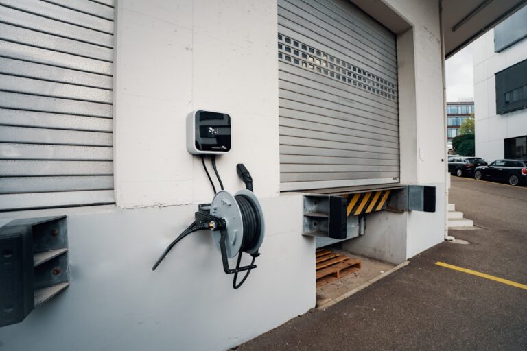 Moderne Wallbox an Hauswand mit angeschlossenem Elektroauto im Alltag